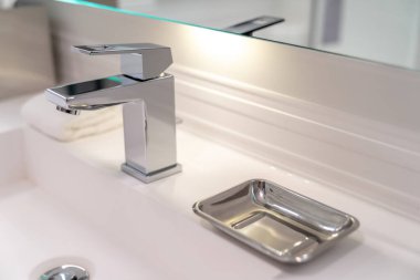 Modern lavabo musluğu ve sabunluk otel banyosunda.