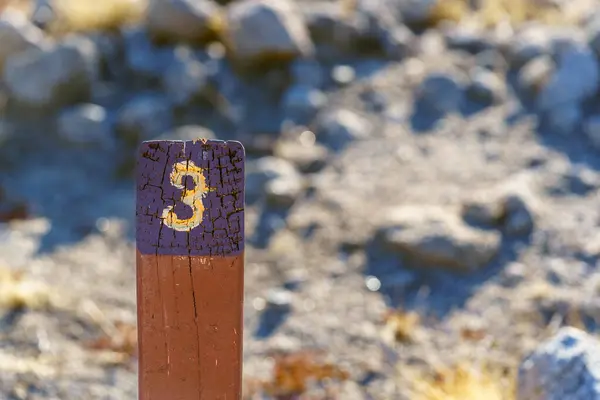 Trail Mile Marker Number Three (3) carved on a wooden post and painted yellow