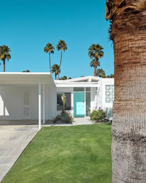 Palm Springs, Kaliforniya 'da mavi yeşil kapısı olan beyaz orta çağ modern evi.