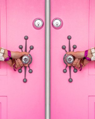 Pink door with a woman's hands holding the doorknobs in Palm Springs, California clipart