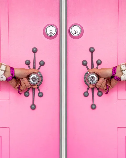 Pink door with a woman\'s hands holding the doorknobs in Palm Springs, California