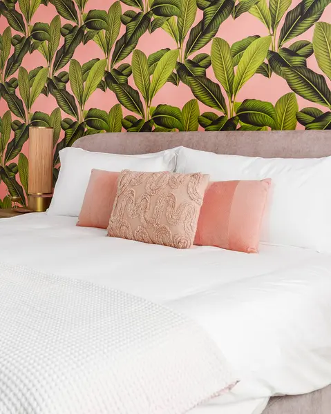 Bedroom with pink and green accent colors and tropical wallpaper theme