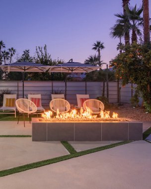 Geceleri Palm Springs, Kaliforniya 'da şöminesi ve sandalyeleri olan bir bahçe avlusu.