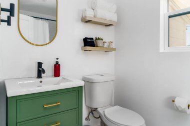 Yeşil dolaplı beyaz banyo ve kiralık evde lavabosu olan pirinç donanım.