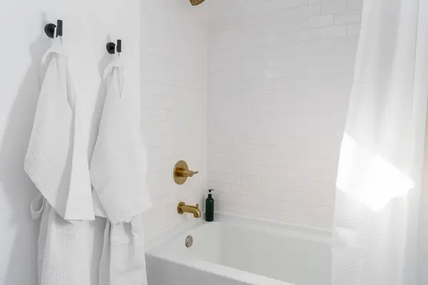 Beyaz banyo küveti, pirinç teçhizat ve banyo bornozu kiralık.