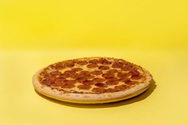 Biberli pizza, arka plandaki sarı stüdyoda fotokopi alanı ile çekilmiştir.