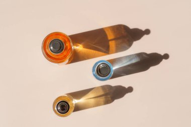 Parlak kırılan ışık ve yukarıdan gelen sert gölgelerle renkli parfüm şişeleri.