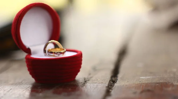 木桌上红色盒子里的结婚戒指 — 图库照片