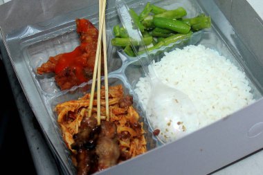 Geleneksel Mutfak, Endonezya 'nın tipik yemekleri, içinde pirinç, tavuk satay, kızarmış yeşil fasulye, doğranmış tavuk ve biber sosu bulunan pirinç kutusu menüsü..