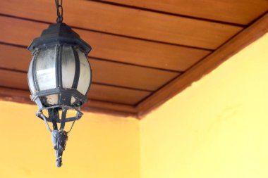 Evin önündeki ahşap tavandan sarkan eski bir Cava tarzı cam lamba..