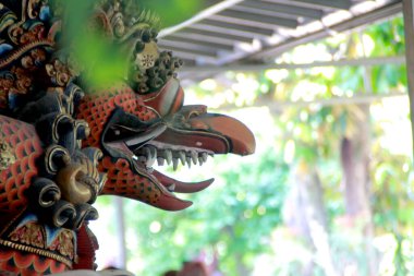  Garuda Vishnu Kencana ahşap heykelinin ayrıntıları, gün boyunca ağaçların ve bokeh 'in arka planında.