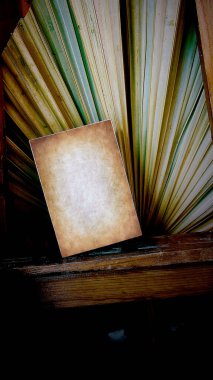 Eski kağıt motifleri olan kitap sayfaları, arka planda kuru palmiye yaprakları olan uzun tahta bir masa üzerinde.
