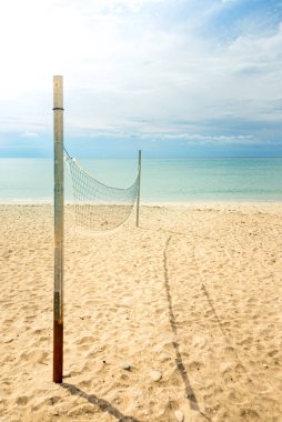 Beach volleyball net on a golden sand beach with turquoise sea waters and bright blue sunny sky