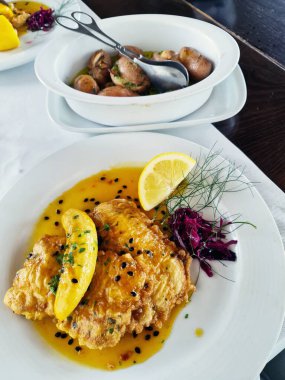 Muzlu ve tutkulu meyve soslu Filete de Espada. Kara Kılıçbalığı - Madeira adasındaki en tipik balık. Beyaz tabakta yanında patates olan tipik bir Espada yemeği..