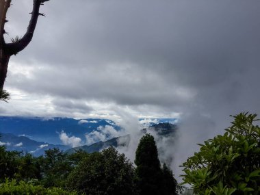 Ağaçlarla, bulutlarla ve mavi gökyüzüyle kaplı dağlar.