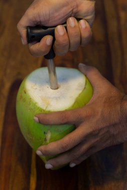 Tahta bir platforma karşı hindistan cevizi açarken çekilmiş yakın plan bir fotoğraf..