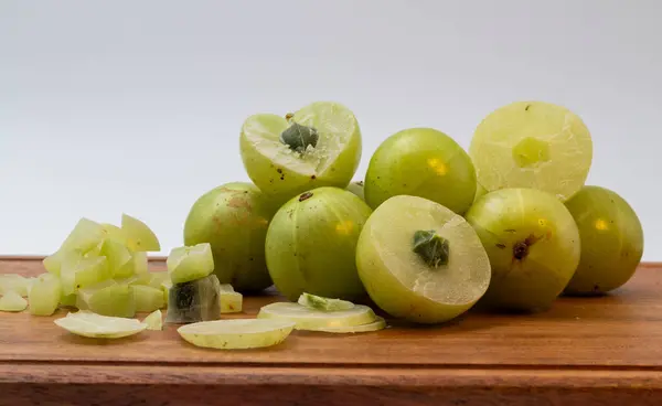 Stock image Top angle shot of chopped amla and whole amla placed on a wooden chopping board.