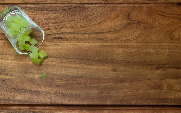 stock image Top angle shot of a chopped amla pouring out of a glass placed on a wooden chopping board.