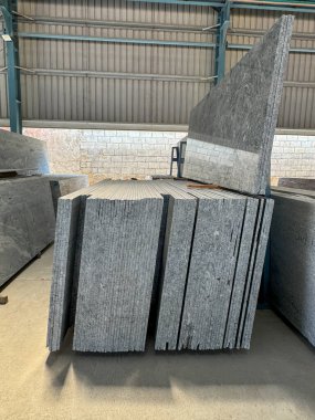 Bir fabrikada dikey olarak istiflenmiş granit levhaların yakın plan çekimi..