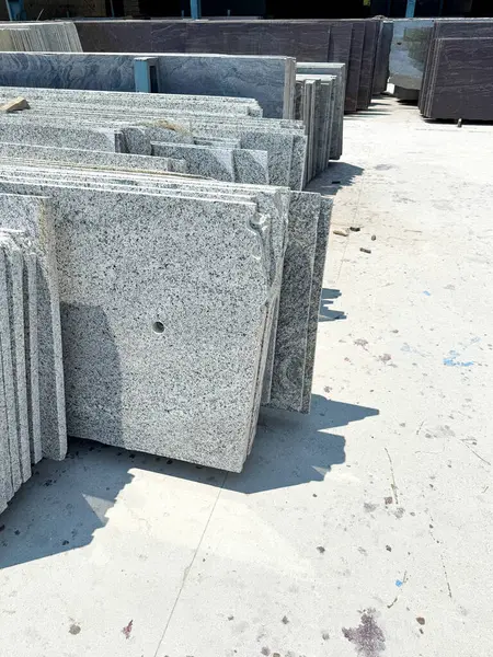 Bir fabrikada dikey olarak istiflenmiş granit levhaların yakın plan çekimi..