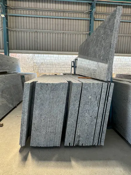 Bir fabrikada dikey olarak istiflenmiş granit levhaların yakın plan çekimi..