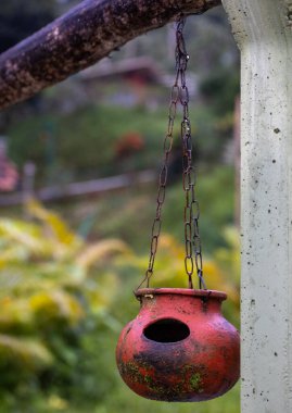 Kuşlar su içsin diye bahçedeki bir direğe asılmış tencere.