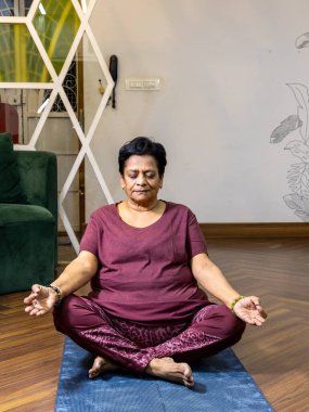 Yoga minderinde oturmuş meditasyon yapan bir kadının yakın çekimi.