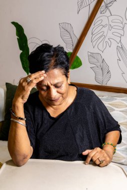 Baş ağrısı ve rahatsızlık belirtileri gösteren bir bayanın yakın plan fotoğrafı.