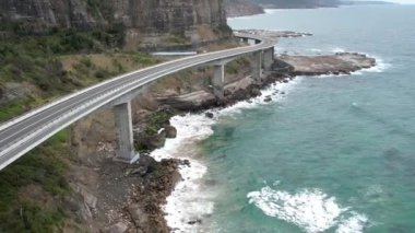Pasifik kıyılarındaki Sea Cliff Köprüsü 'nün havadan görüntüsü Wollongong, Illawarra, Yeni Güney Galler, Avustralya. 665 metre uzunluğundaki Köprü, Büyük Pasifik Yolu boyunca önemli bir noktadır. Köprü Wollongong halkı ve dünya için bir ikondur..