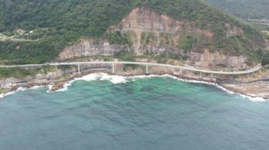 Pasifik kıyılarındaki Sea Cliff Köprüsü 'nün havadan görüntüsü Wollongong, Illawarra, Yeni Güney Galler, Avustralya. 665 metre uzunluğundaki Köprü, Büyük Pasifik Yolu boyunca önemli bir noktadır. Köprü Wollongong halkı ve dünya için bir ikondur..