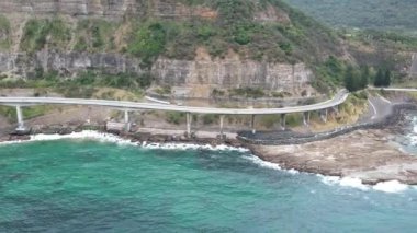 Pasifik kıyılarındaki Sea Cliff Köprüsü 'nün havadan görüntüsü Wollongong, Illawarra, Yeni Güney Galler, Avustralya. 665 metre uzunluğundaki Köprü, Büyük Pasifik Yolu boyunca önemli bir noktadır. Köprü Wollongong halkı ve dünya için bir ikondur..