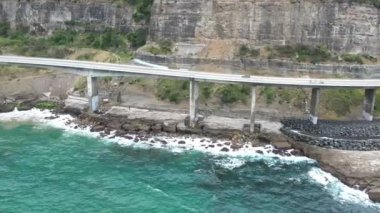 Pasifik kıyılarındaki Sea Cliff Köprüsü 'nün havadan görüntüsü Wollongong, Illawarra, Yeni Güney Galler, Avustralya. 665 metre uzunluğundaki Köprü, Büyük Pasifik Yolu boyunca önemli bir noktadır. Köprü Wollongong halkı ve dünya için bir ikondur..