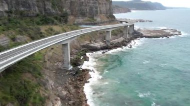Pasifik kıyılarındaki Sea Cliff Köprüsü 'nün havadan görüntüsü Wollongong, Illawarra, Yeni Güney Galler, Avustralya. 665 metre uzunluğundaki Köprü, Büyük Pasifik Yolu boyunca önemli bir noktadır. Köprü Wollongong halkı ve dünya için bir ikondur..