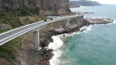 Pasifik kıyılarındaki Sea Cliff Köprüsü 'nün havadan görüntüsü Wollongong, Illawarra, Yeni Güney Galler, Avustralya. 665 metre uzunluğundaki Köprü, Büyük Pasifik Yolu boyunca önemli bir noktadır. Köprü Wollongong halkı ve dünya için bir ikondur..