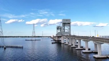 James River Lift Köprüsü JRB, yüksek kuleler ve görünür kablolarla desteklenen sakin bir su geçidini kapsar. Bu altyapı uzak kıyıları birbirine bağlıyor, parlak ve berrak bir gökyüzünün altındaki mavi suyu yansıtıyor.