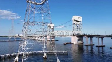 James River Lift Köprüsü JRB, yüksek kuleler ve görünür kablolarla desteklenen sakin bir su geçidini kapsar. Bu altyapı uzak kıyıları birbirine bağlıyor, parlak ve berrak bir gökyüzünün altındaki mavi suyu yansıtıyor.