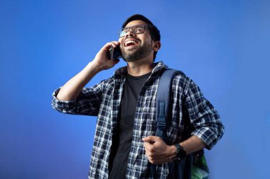 Bir üniversite erkek öğrencisinin portresi mutlu bir şekilde telefonda gülüyor ve konuşuyor..