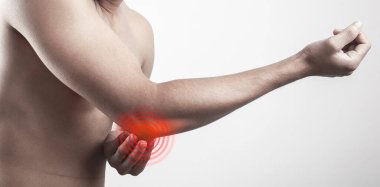 Gömleksiz, ince bir adamın dirsek eklemine acıyla dokunuşunun yakın görüntüsü. Acı veren bölge kırmızı ışıkla vurgulanıyor..