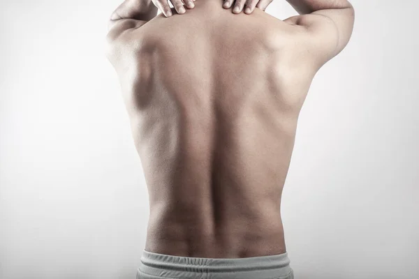 A shirtless man touching his shoulder injury pain on levator scapulae isolated in black and white background.