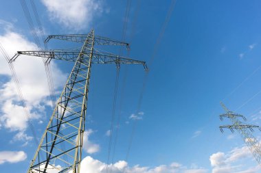 Ulaşım için elektrik direği ve bulutlu bir gökyüzünün önündeki doğal manzaralardan yüksek voltaj transferi