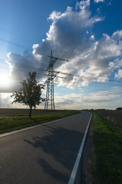 stock image Electricity pylon for transmission and current transfer of high voltage through natural landscapes in front of a cloudy sky