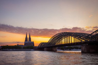 The Cologne Cathedral (Klner Dom) and Hohenzollern Bridge over the Rhine River in Cologne, Germany, create a stunning skyline with their iconic Gothic architecture and picturesque views, capturing the city's historic charm and vibrant atmosphere. clipart