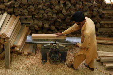 June 12,2023, Srinagar Kashmir, India : A labourer is planing planks for GR8 cricket bats at a manufacturing unit in Sangam, some 38 kilometers south of Srinagar clipart