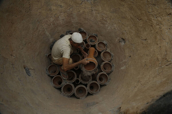 10 августа 2023 года, Шринагар Кашмир, Индия: Абдул Рашид Кумар, кашмирский гончар вынимает земляной барабан Tumbaknari (кашмирский музыкальный барабан) из печи на окраине Шринагара. На кашмирских свадьбах традиционная музыка имеет огромный культурный смысл.