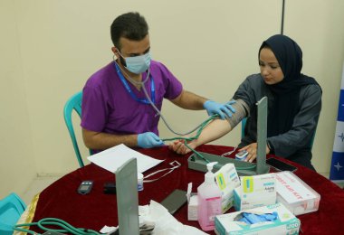 22 Ağustos 2023, Srinagar Kashmir, Hindistan: Srinagar 'daki ücretsiz bir tıp kampı sırasında bir kadın gazetecinin kan basıncını kontrol eden bir doktor