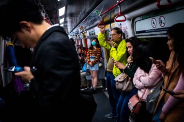 Yolcular Hong Kong 'da yürürken cep telefonlarını kontrol ederler.