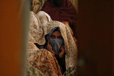Srinagar, Kashmir, Hindistan - 10 Eylül 2023: Bir Kaşmir Müslüman gelini, Srinagar 'da düzenlenen toplu düğün etkinliği sırasında diğer gelinlerle birlikte otururken peçesinden bakar. Hindistan 'da toplu düğünler sosyal kuruluşlar tarafından organize edilir. 