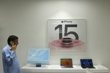 23 Eylül 2023, Srinagar Kashmir, Hindistan: Bir adam Srinagar 'daki bir elektronik mağazasında iPhone 15 reklamının yanında telefonla konuşuyor