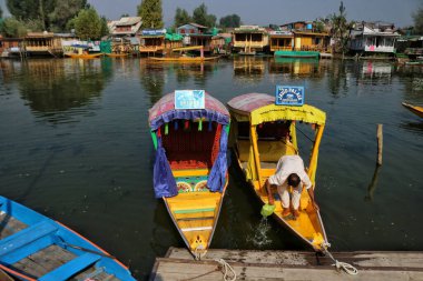 Srinagar Kashmir, Hindistan - 27 Eylül 2023: Srinagar 'da düzenlenen Dünya Turizm Günü sırasında Kaşmirli bir adam teknesini Dal Gölü' nün sularında temizliyor. Turizm, tarım dışında Kaşmir ekonomisinin ana merkezlerinden biridir. 