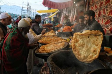 Srinagar Kashmir, Hindistan - 29 Eylül 2023: İnsanlar Srinagar 'daki Hazretbal tapınağının dışındaki bir satıcıdan yerel atıştırmalıklar satın alıyor. 